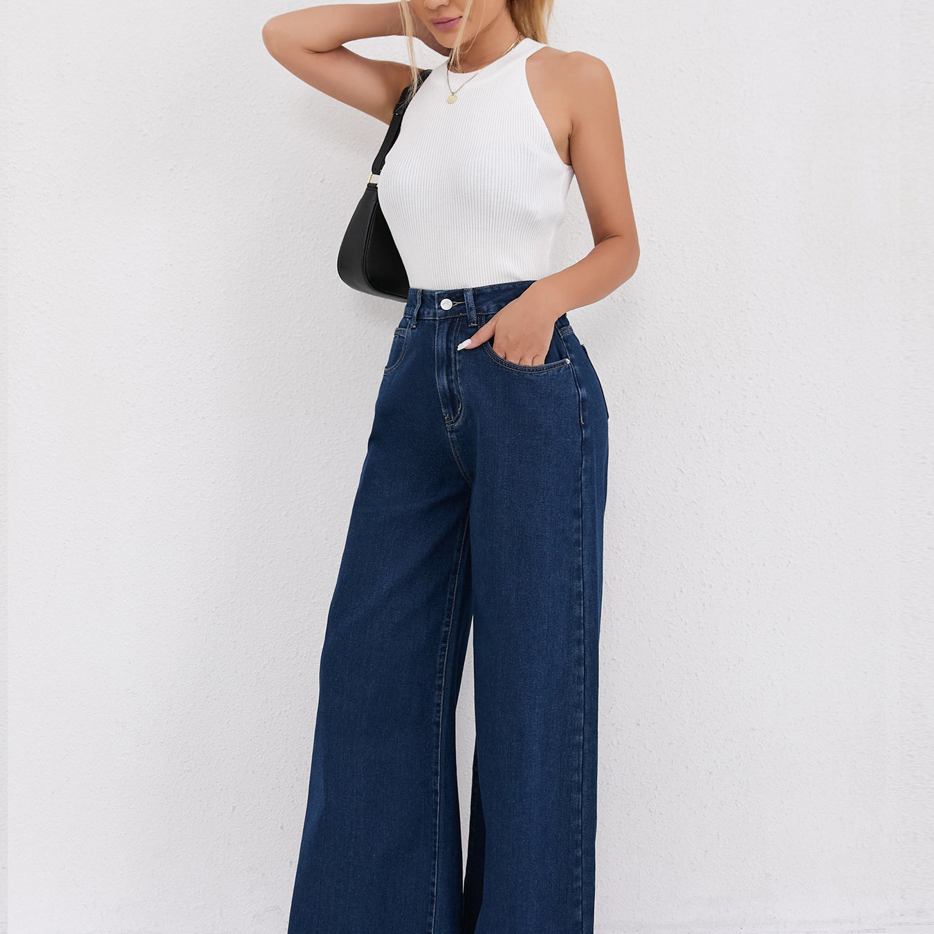 Wide leg dark blue denim jeans with white sleeveless top in stylish fashion ensemble