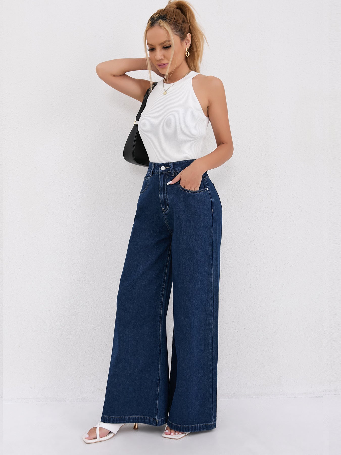 Wide leg dark blue denim jeans with white sleeveless top in stylish fashion ensemble
