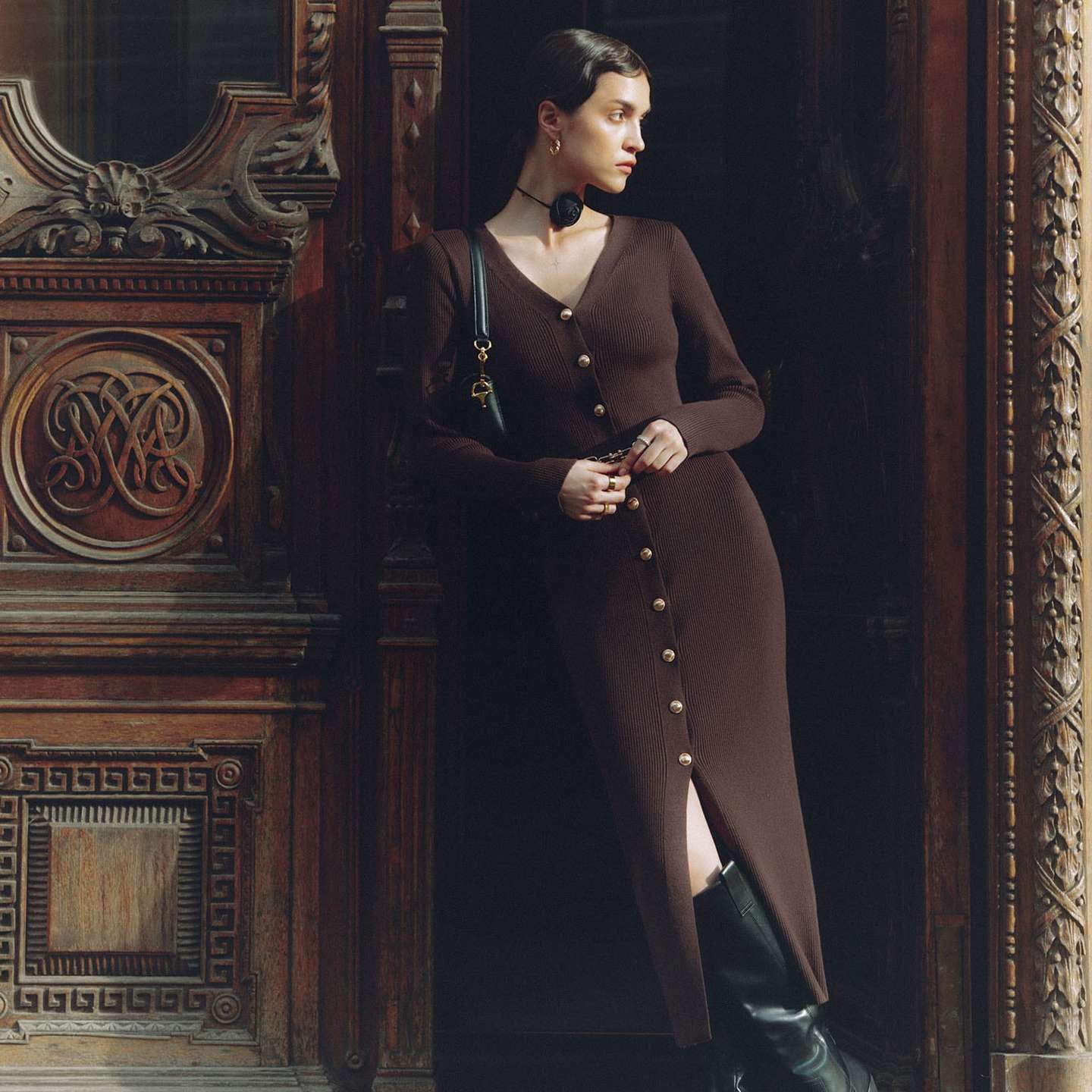 Woman in long sleeve knitted dress and black boots showcasing elegant fashion style