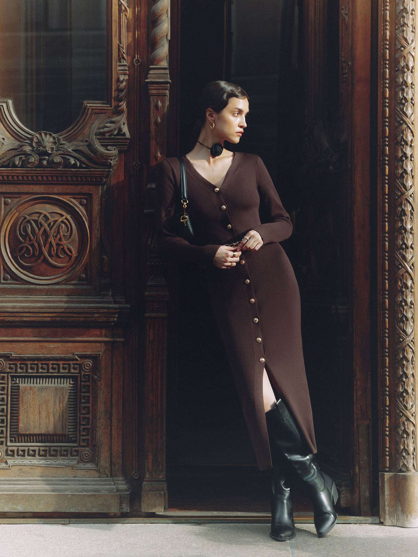 Woman in long sleeve knitted dress and black boots showcasing elegant fashion style