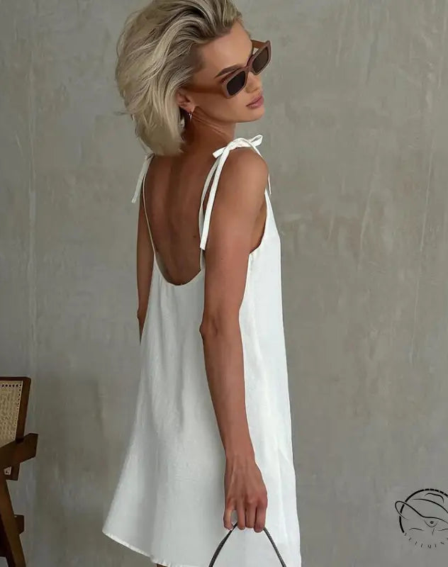 Woman in white backless cotton home wear slip dress with tie straps