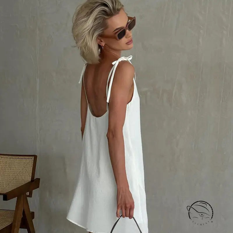 Woman in white backless cotton home wear slip dress with tie straps