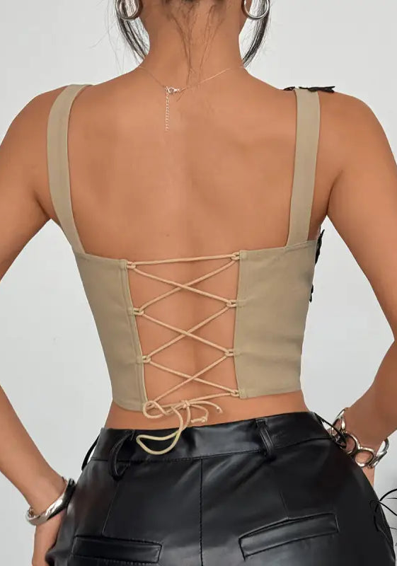 Beige lace-up lace corset top with thin straps and black leather pants