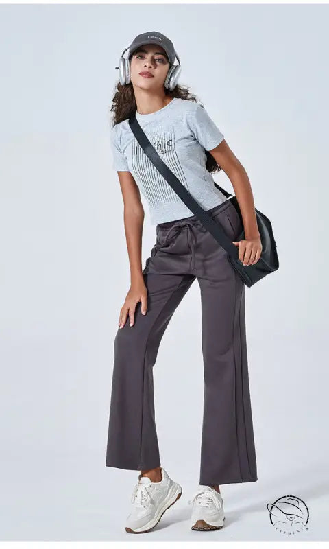 Woman in summer air layer white striped t-shirt, gray wide-leg pants, white sneakers, black crossbody bag