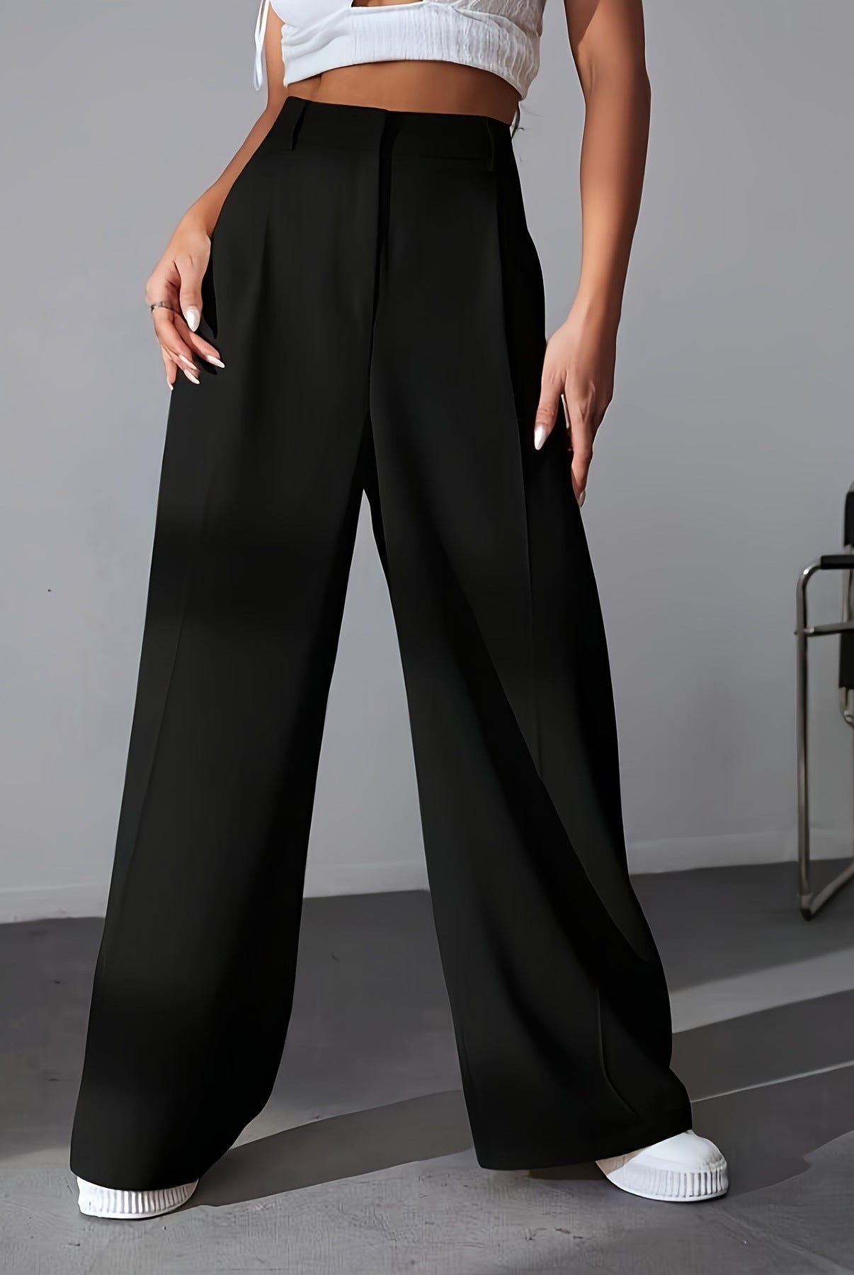 Black high-waisted wide leg trousers with white sneakers for a stylish fashion look