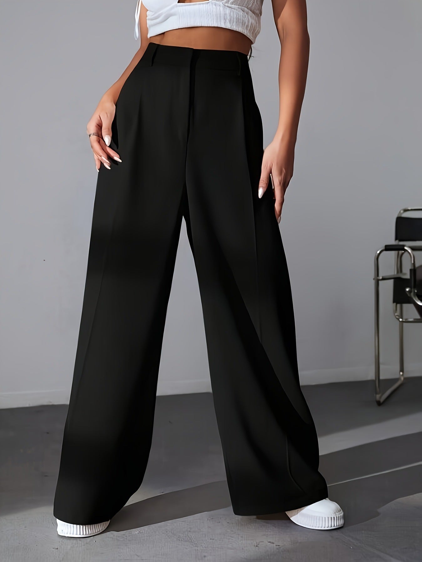 Black high-waisted wide leg trousers with white sneakers for a stylish fashion look