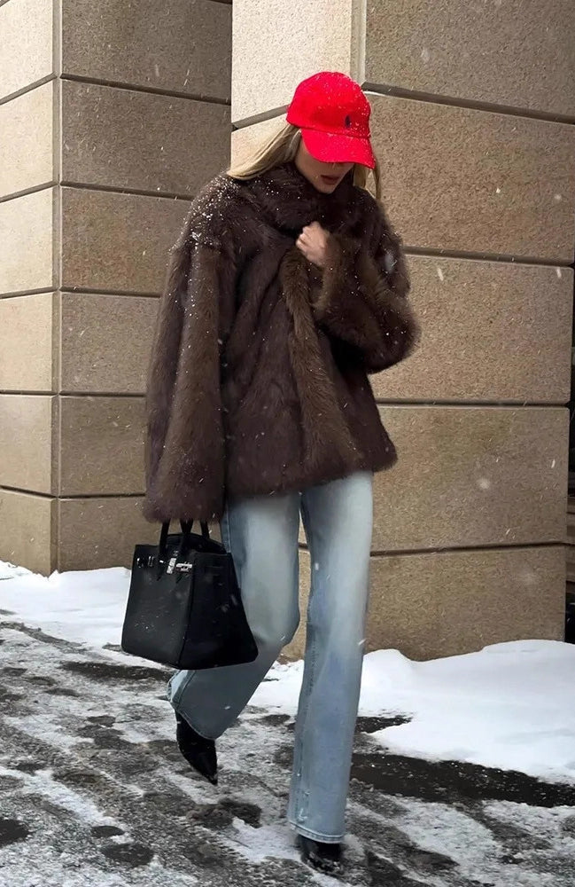 Fashionable warm faux fur coat with black leather handbag and silver hardware