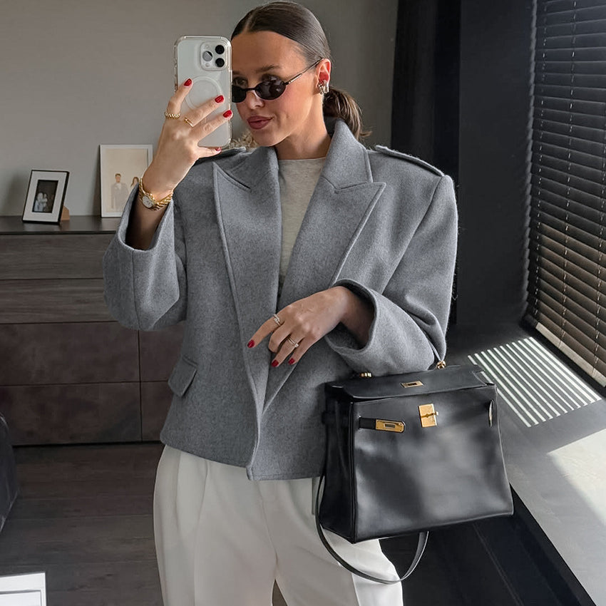 Langry fashion gray wool blazer with oversized sleeves and large lapels, paired with black leather handbag featuring silver hardware