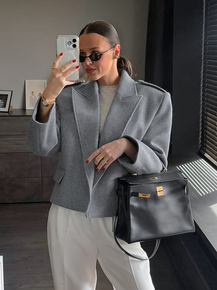 Langry fashion gray wool blazer with oversized sleeves and large lapels, paired with black leather handbag featuring silver hardware