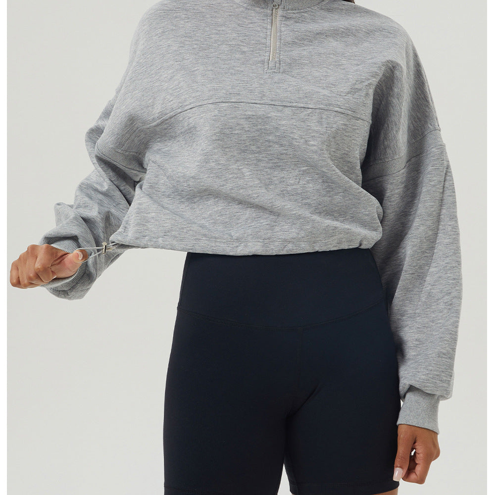 Gray long sleeve quarter-zip sweatshirt paired with black biker shorts for casual fashion