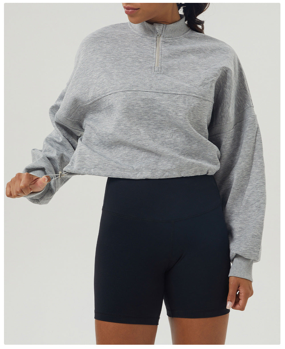 Gray long sleeve quarter-zip sweatshirt paired with black biker shorts for casual fashion