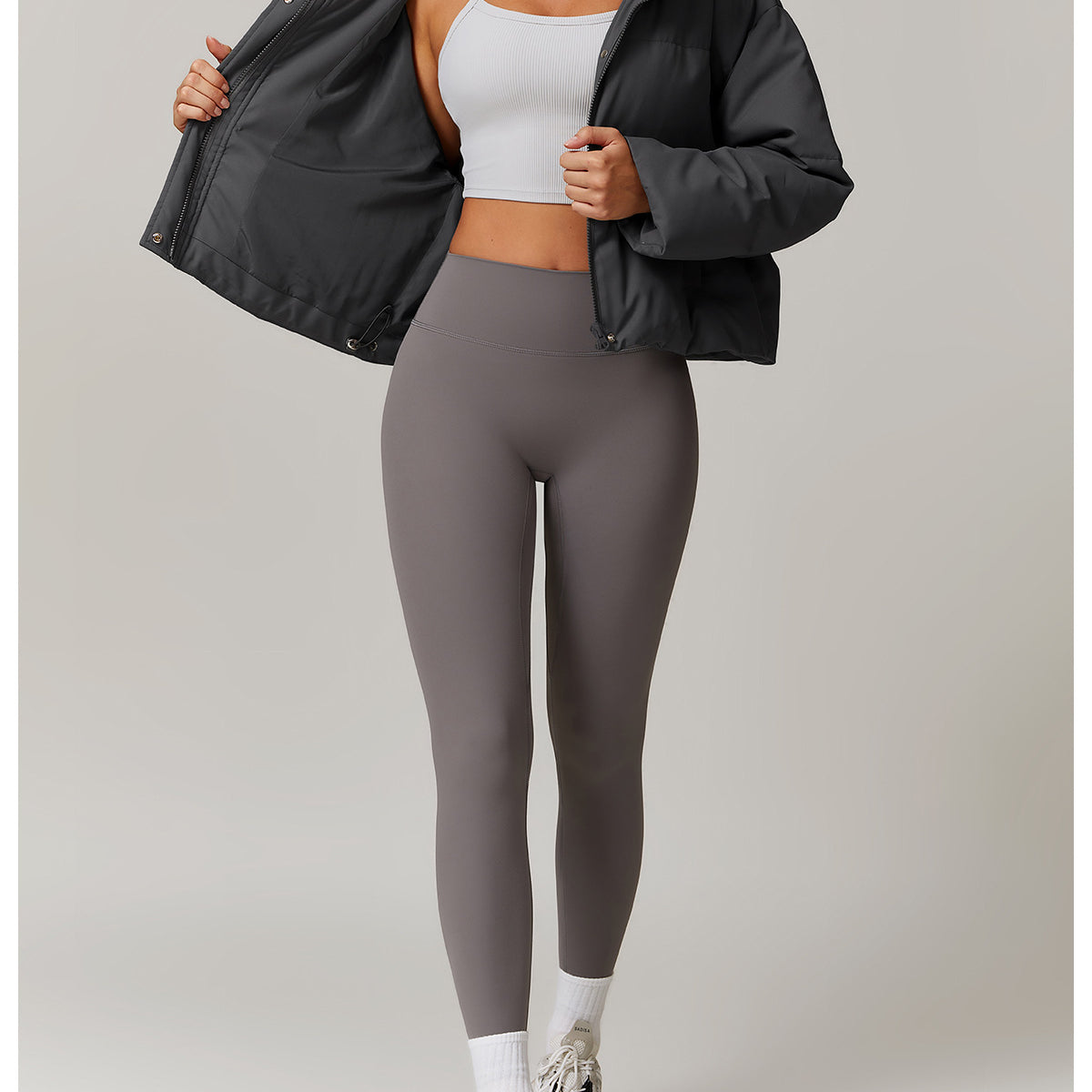 Woman wearing a stylish gray puffer jacket and leggings, perfect for fashionable warmth
