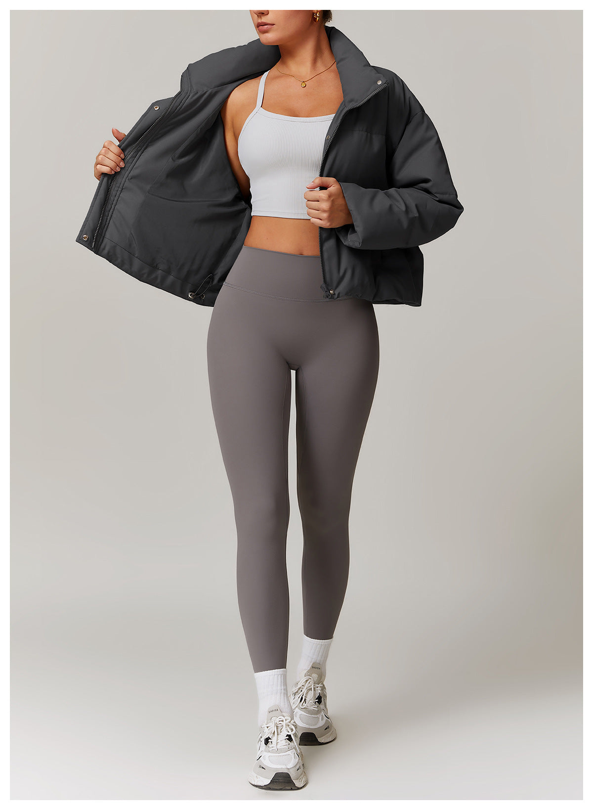 Woman wearing a stylish gray puffer jacket and leggings, perfect for fashionable warmth