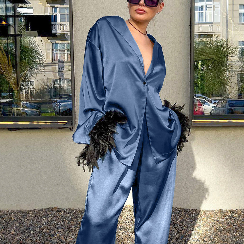Langry fashion blue satin jumpsuit with feather accents and button-down front