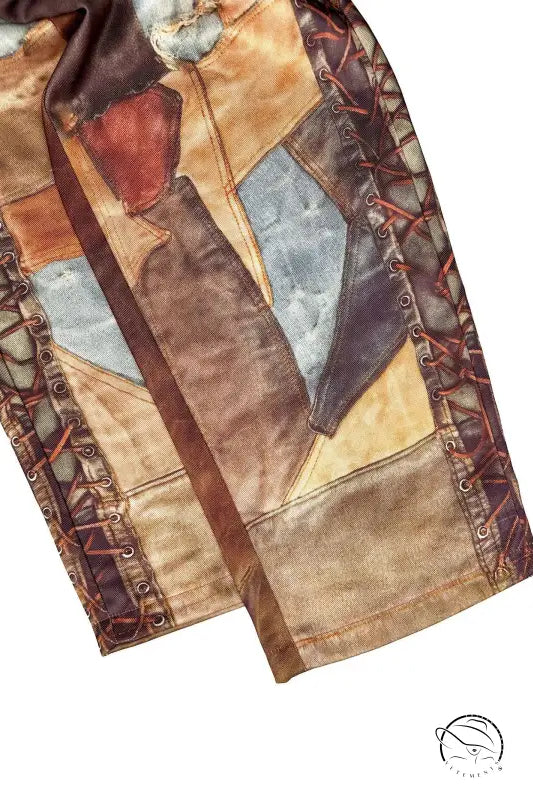 Patchwork leather jacket sleeve with brown, tan, blue geometric panels on casual dirty denim pants