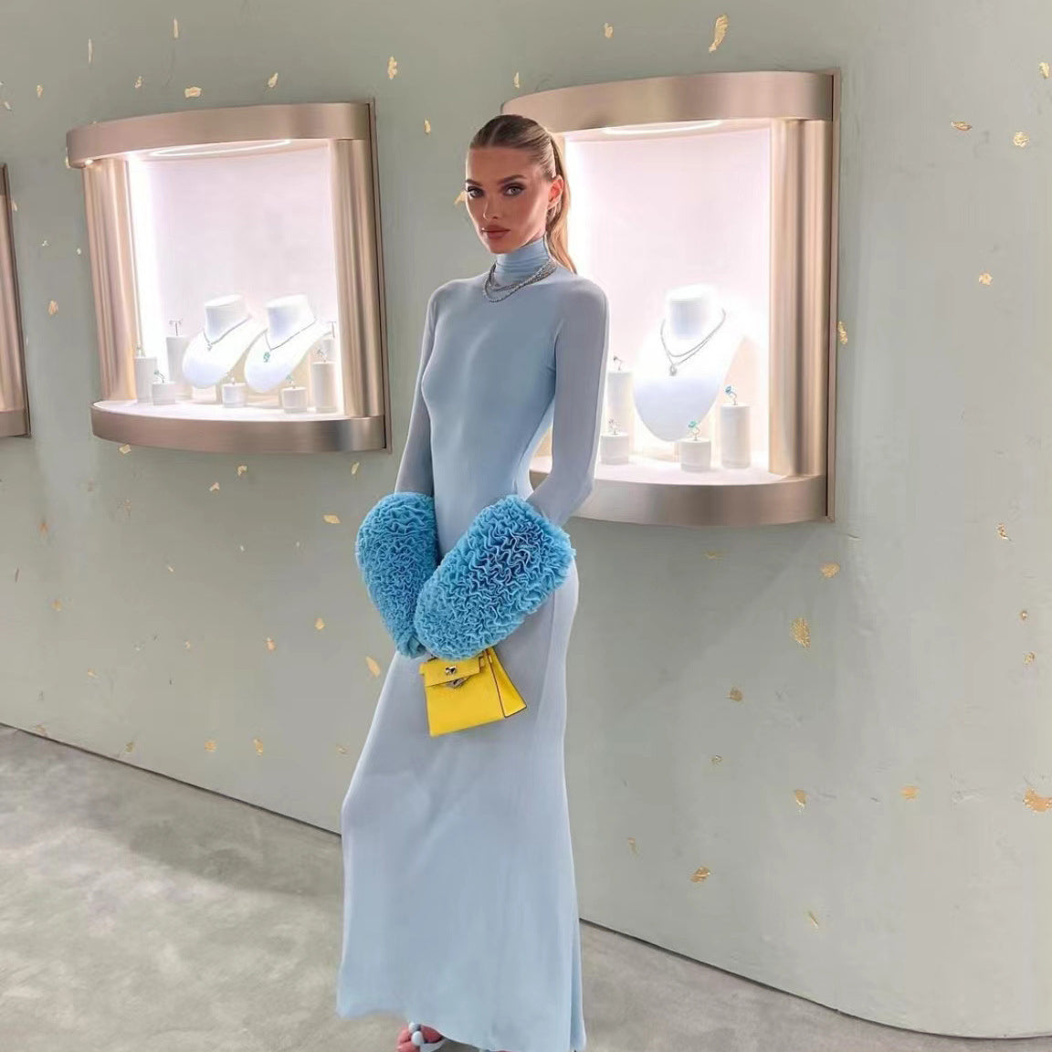 Model in a gorgeous light blue slim fit dress with blue furry hand warmers and yellow purse for fashionable ملابس and langry style