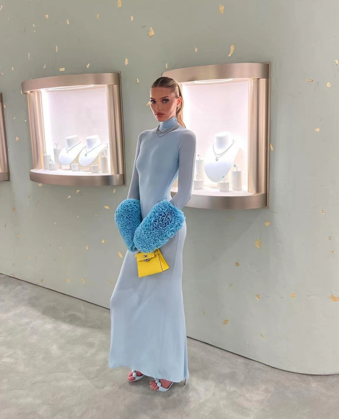 Model in a gorgeous light blue slim fit dress with blue furry hand warmers and yellow purse for fashionable ملابس and langry style