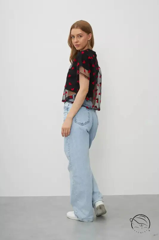 Elegant faux cotton short top: model in sheer floral blouse and light blue jeans against plain backdrop