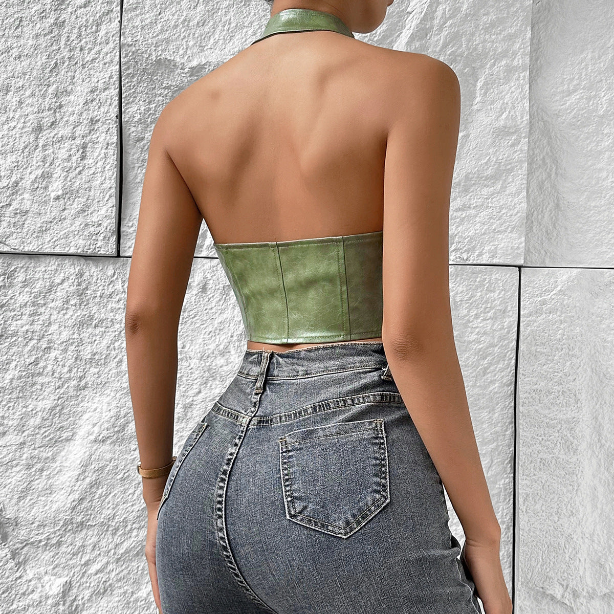 Woman wearing a distressed olive green solid color halter top and dark wash jeans