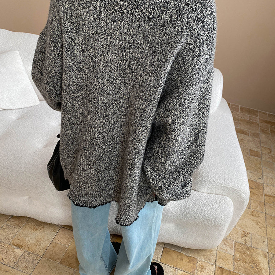 Fashionable double pocket loose knitted sweater in gray and white speckles with black gloves and light blue jeans