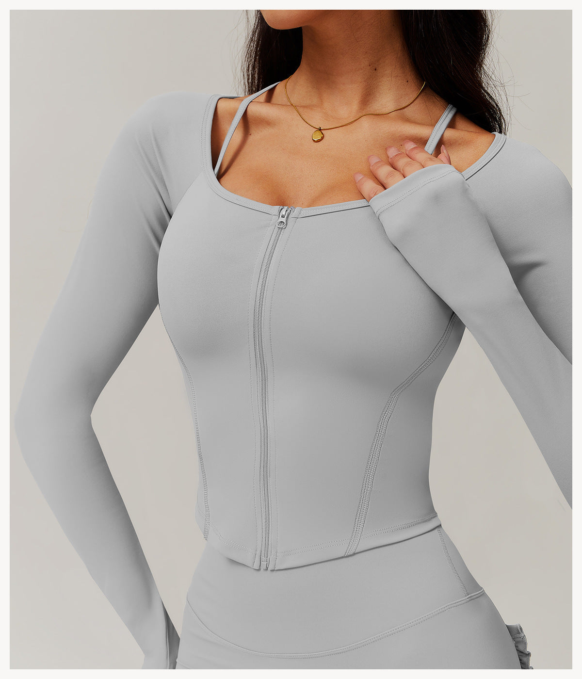 Light gray zip-up athletic top with long sleeves, ideal for comfy fitness and yoga fashion