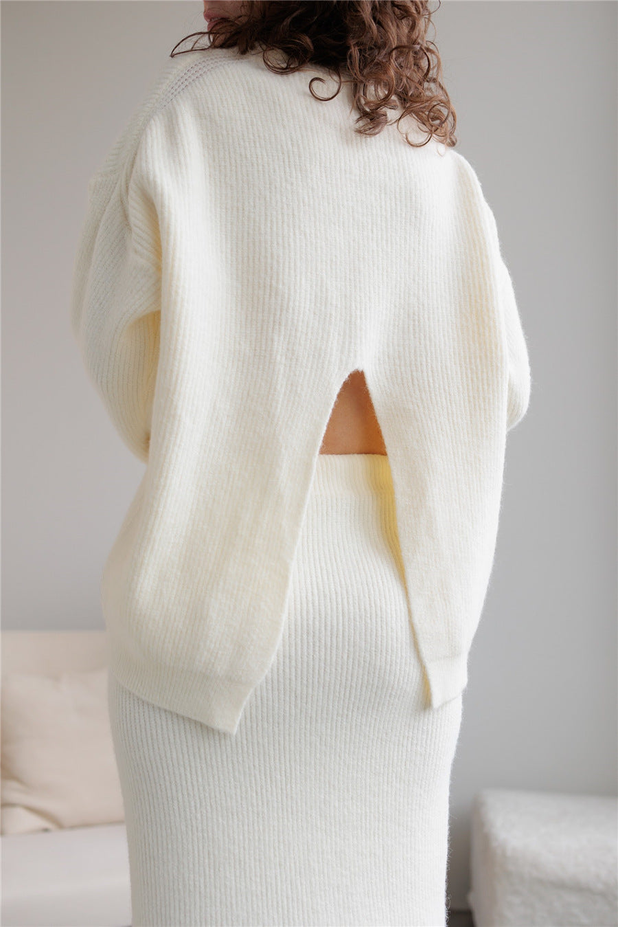 Cream-colored knit sweater and skirt set featuring back cutout in elegant fashion ملابس