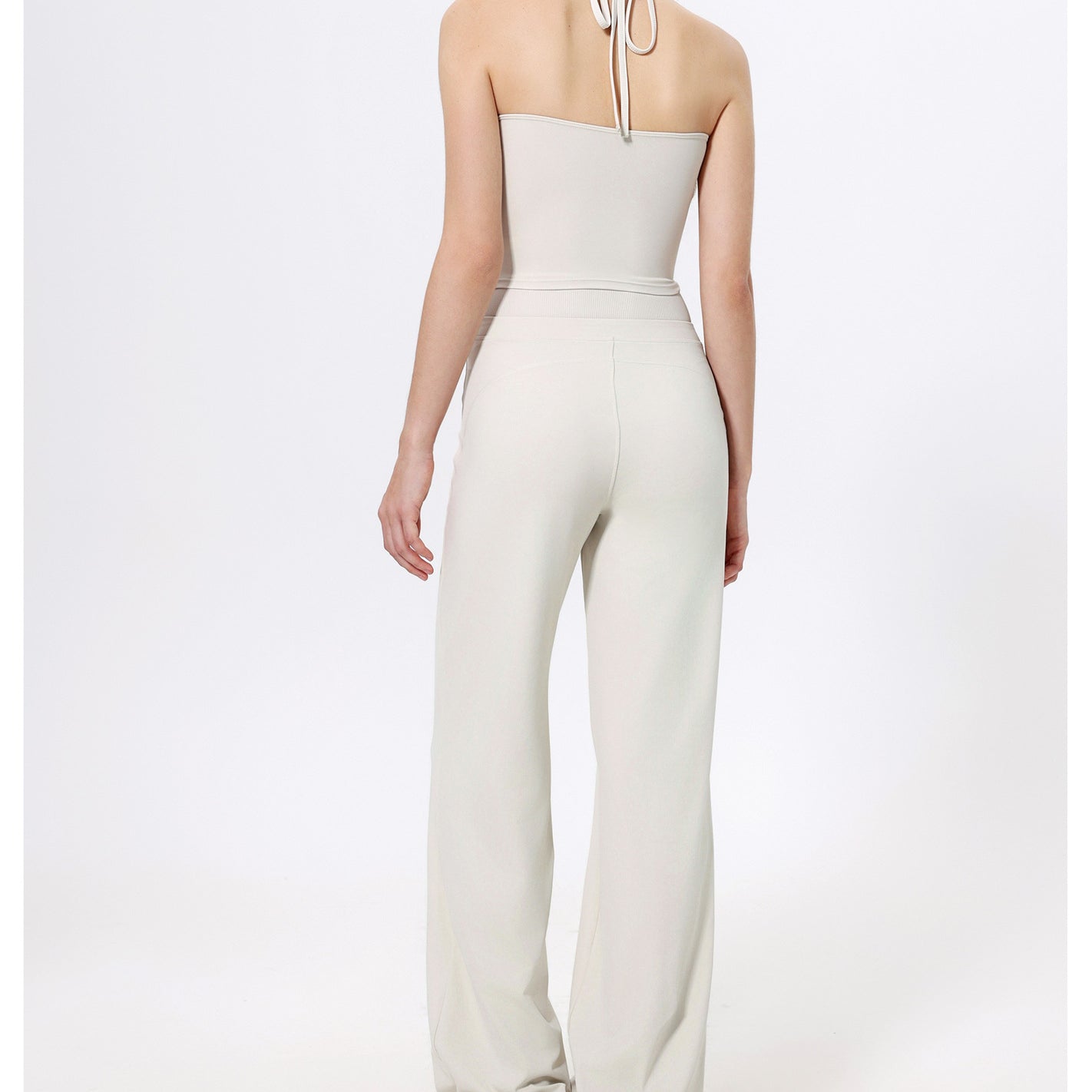 White halter-neck jumpsuit with wide-leg pants and sneakers for trendy fashion ملابس