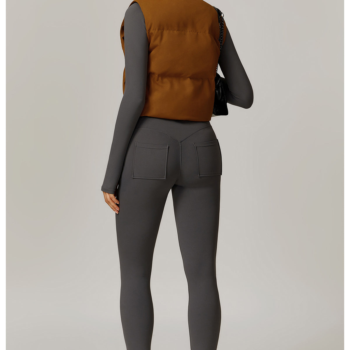 Woman wearing stylish brown puffer vest and gray leggings, perfect for winter fashion