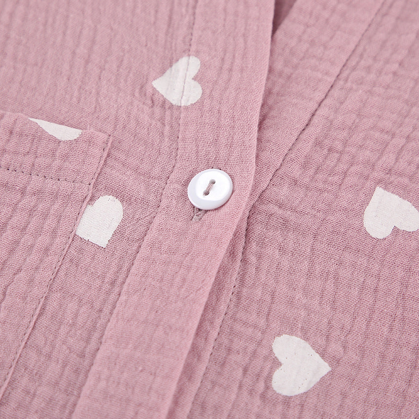 Pink muslin fabric with white heart patterns and a white button, perfect for fashion pajamas set