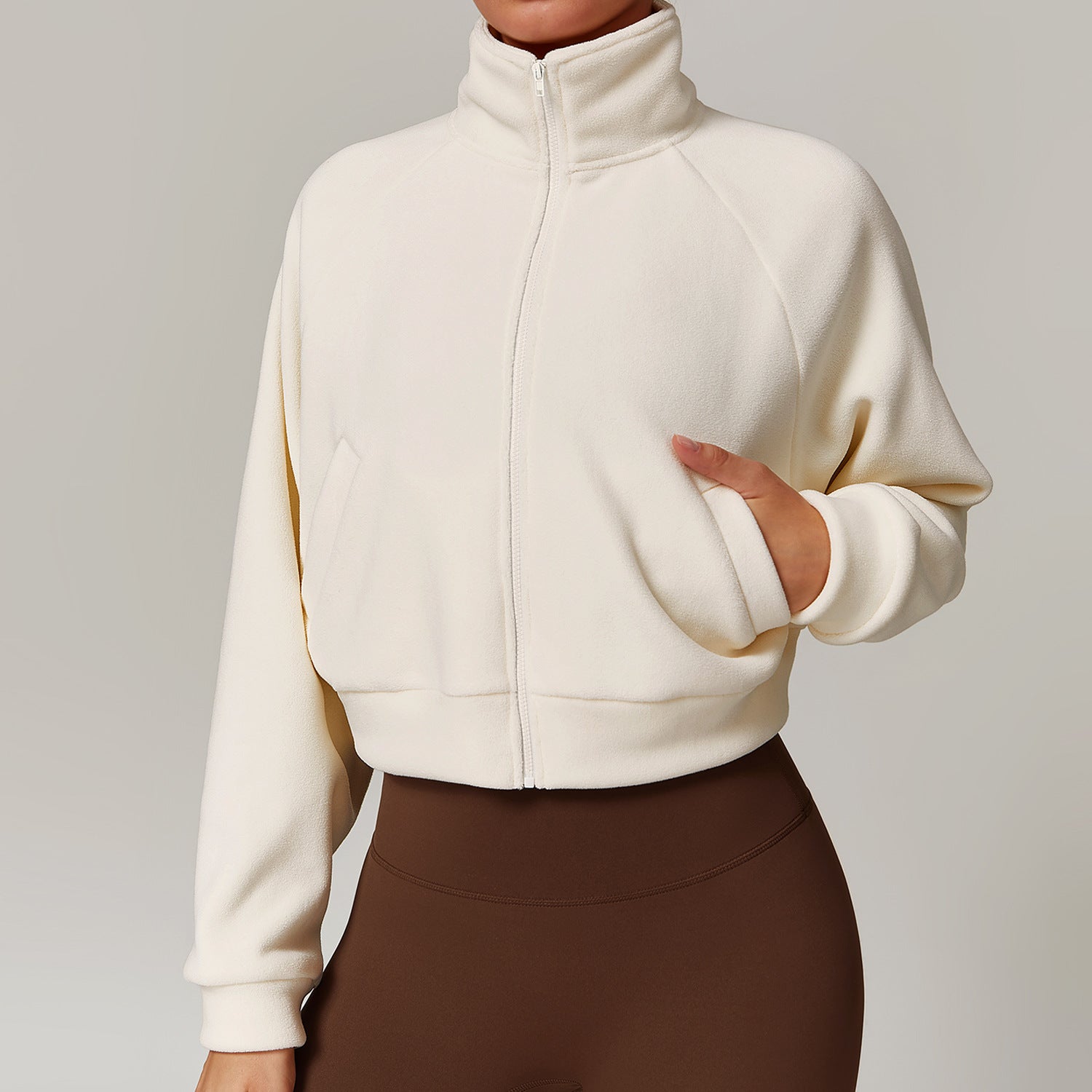 Cream-colored zip-up turtleneck jacket paired with brown skirt for stylish fitness wear