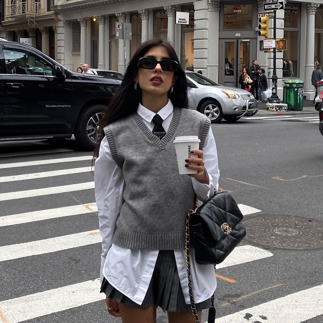 Preppy fashion look featuring gray vest sweater, pleated skirt, and sunglasses with coffee