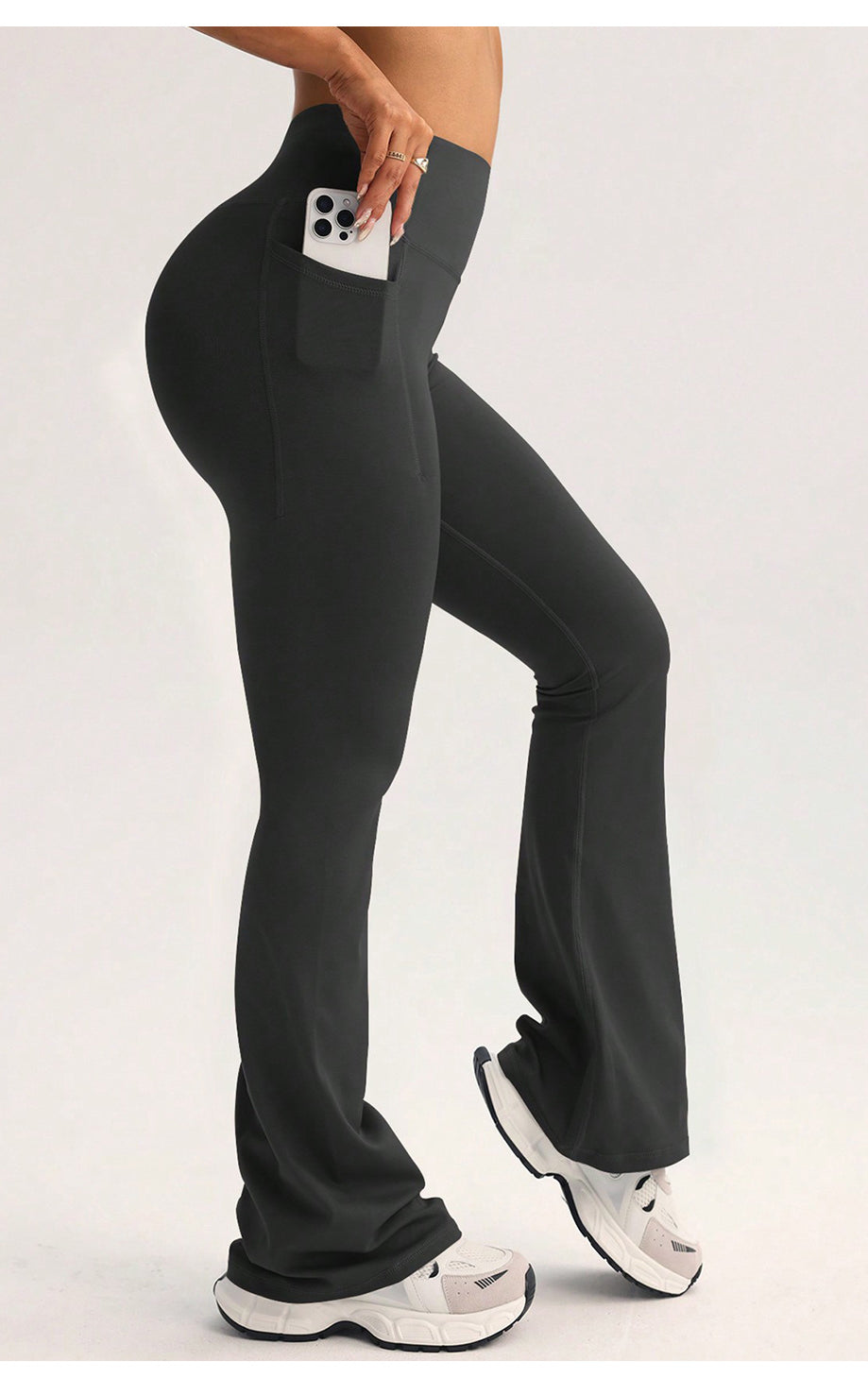 Black high-waisted flared langry yoga pants with side pocket holding white smartphone
