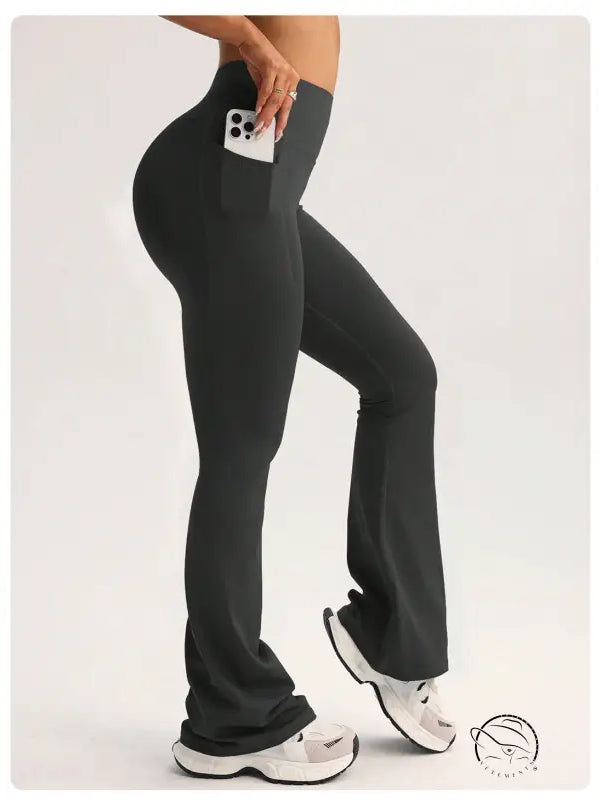 Black high-waisted flared langry yoga pants with side pocket holding smartphone