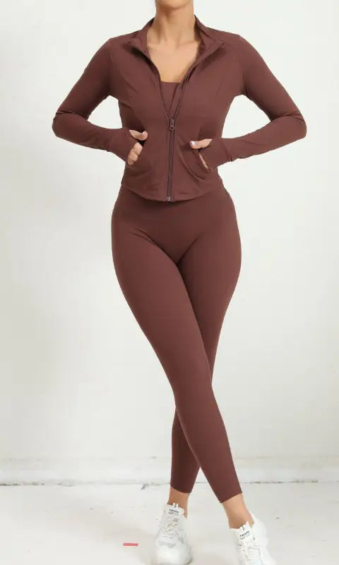 Brown zip-up athletic jacket with matching leggings and white sneakers, three piece yoga clothes suit