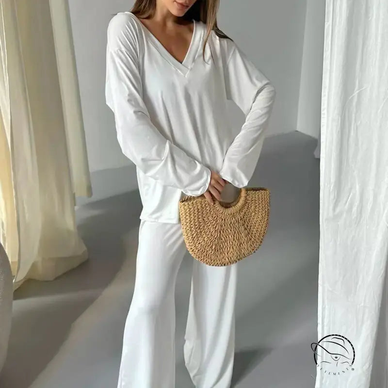 Woman in comfortable knitted pajamas with white V-neck top, wide-leg pants, and straw handbag