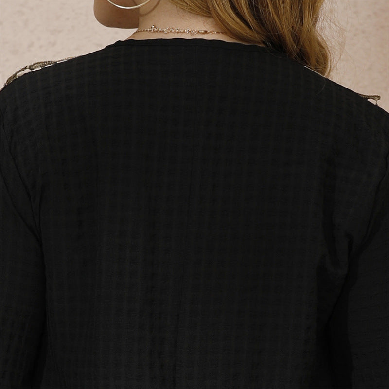 Elegant person wearing a black robe dress with flared sleeves and a gold chain necklace