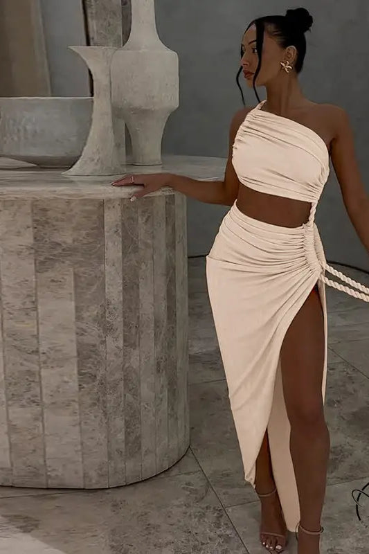 Woman in stunning cutout lace pleated dress with one-shoulder top and high-slit skirt