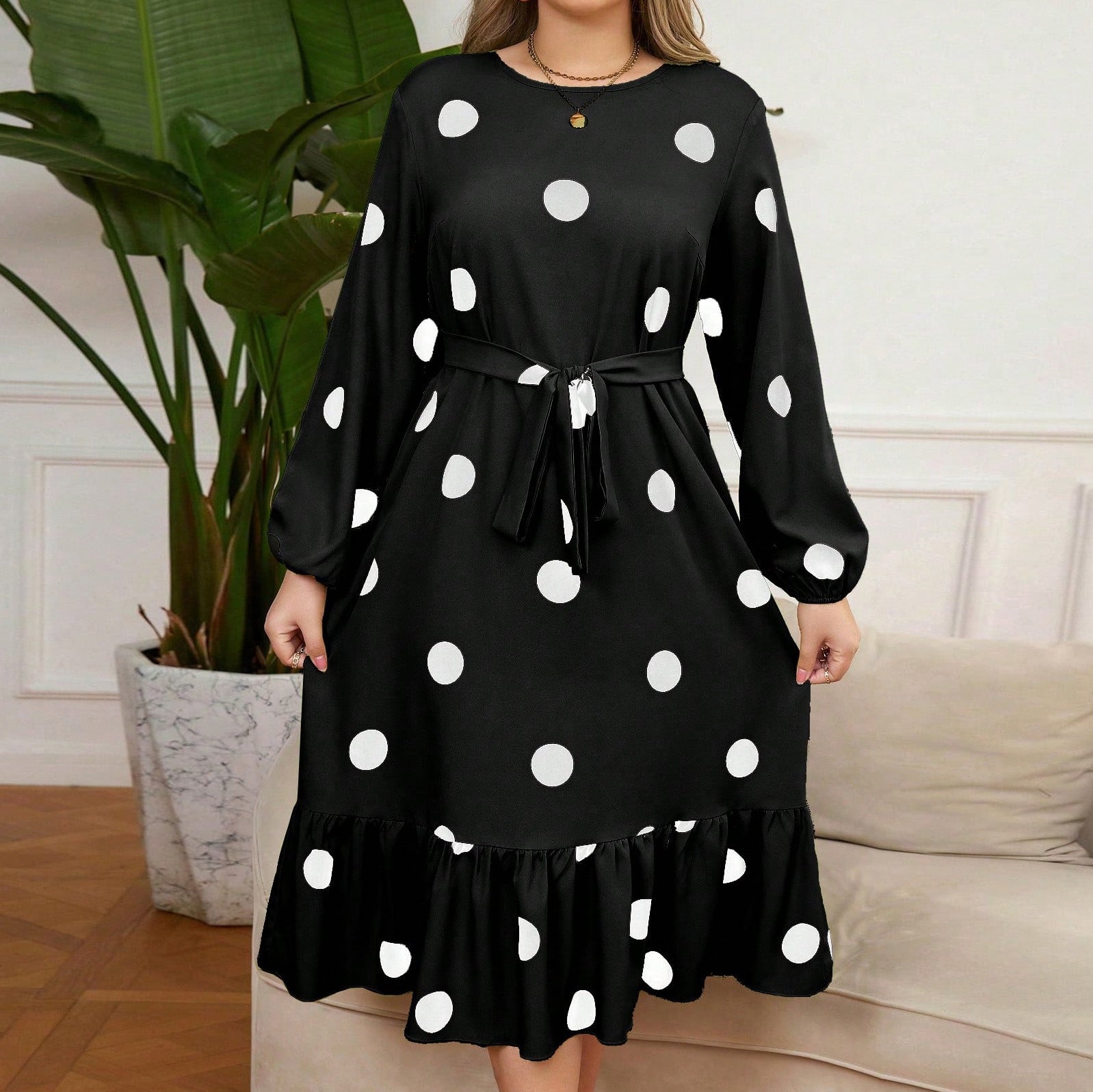 Black knee-length Lotus Leaf Dress with white polka dots, puff sleeves, and tie waist