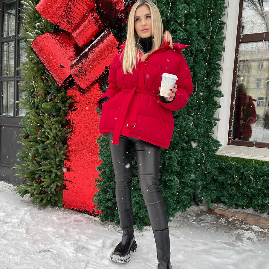 Fashionable woman in red winter coat holding white cup, showcasing ملابس for warmth