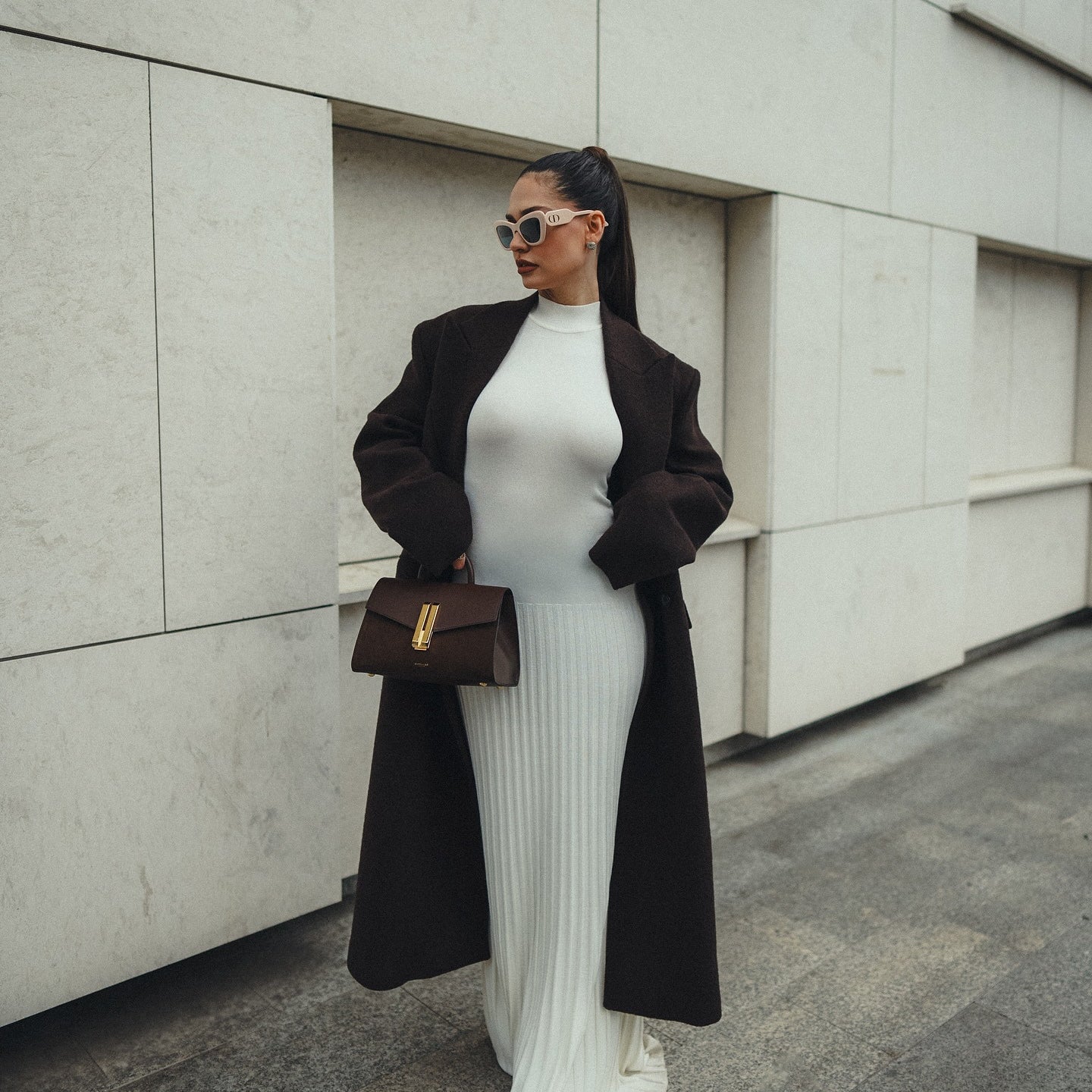 Stylish white ribbed maxi dress paired with a black coat and brown handbag for fashion
