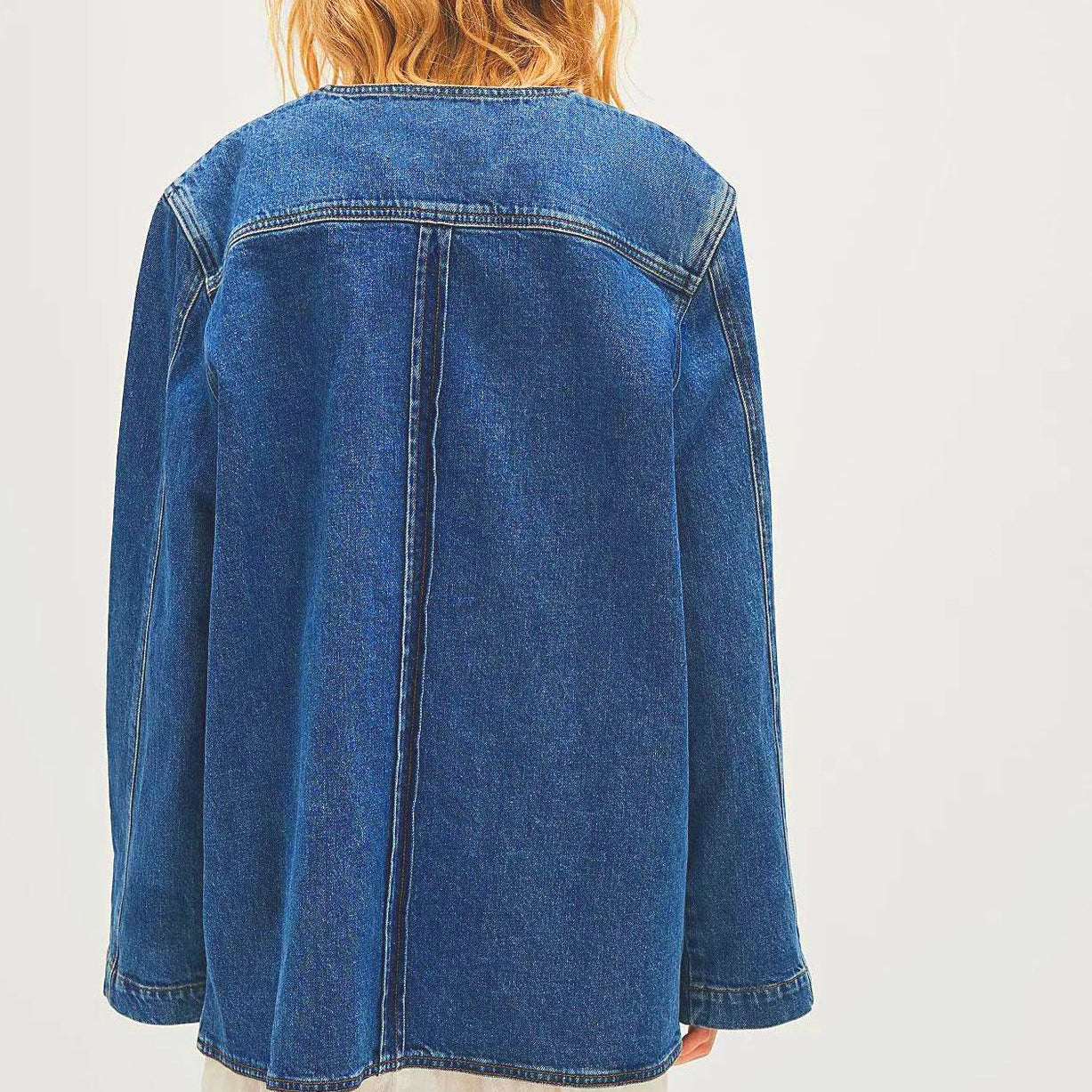 Woman wearing casual fashionable cowboy coat with oversized denim jacket over white dress