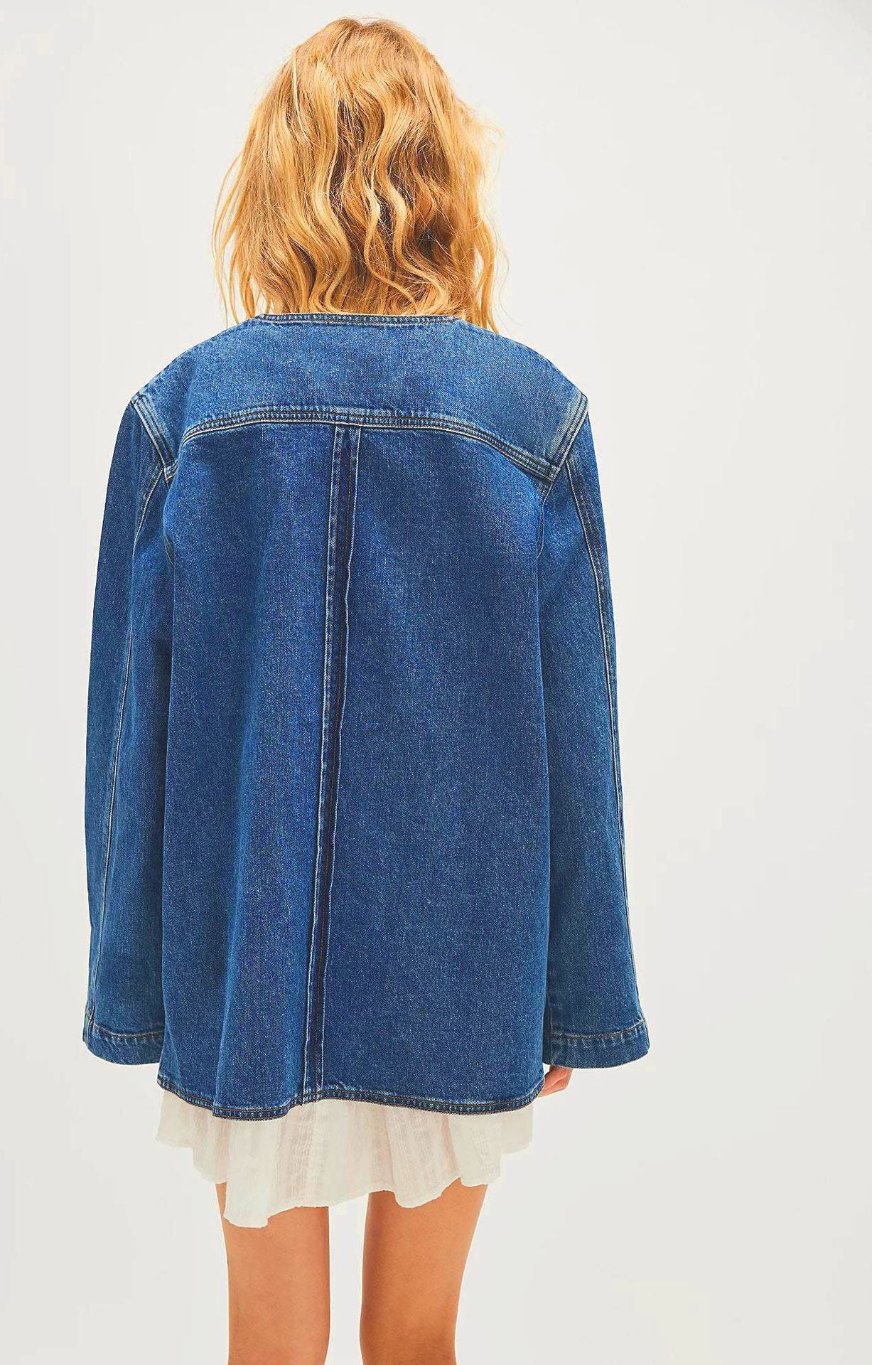 Woman wearing casual fashionable cowboy coat with oversized denim jacket over white dress