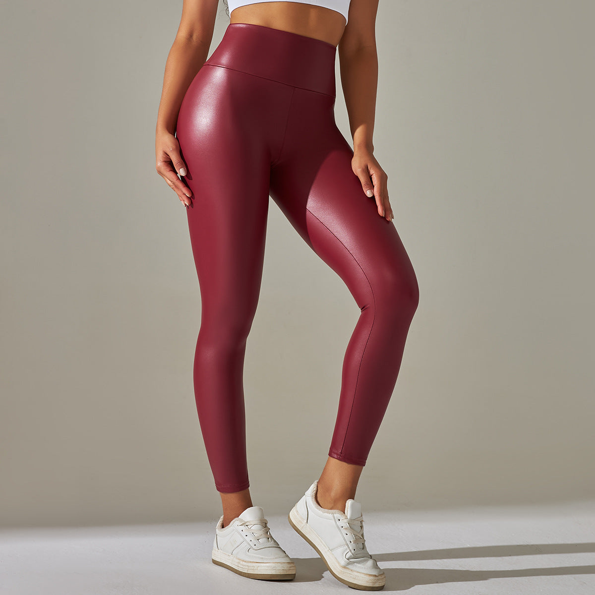 Burgundy high waist faux leather leggings with white sneakers and sports bra