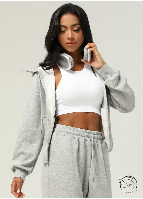 Woman in gray sweatsuit and white sports bra wearing casual cardigan sweater