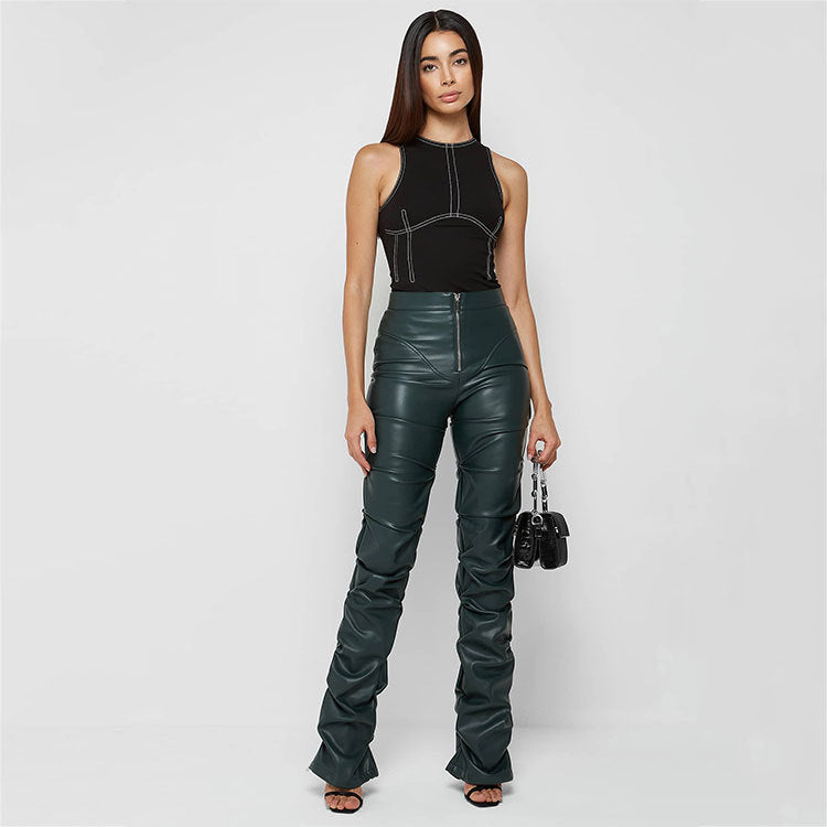 Faux leather woman in black top and green leather pants showcasing fashionable style