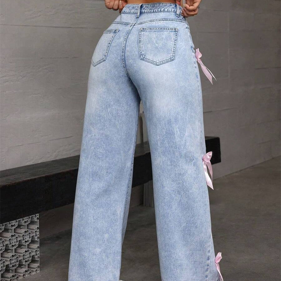 Light wash denim loose straight leg jeans with pink ribbon bows along the sides