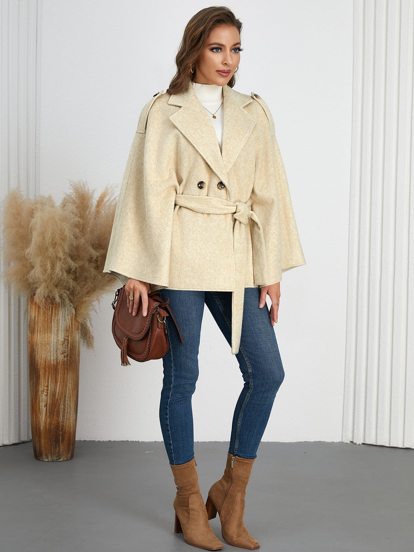 Woman in a belted beige cape coat, showcasing elegant winter fashion ملابس from Langry