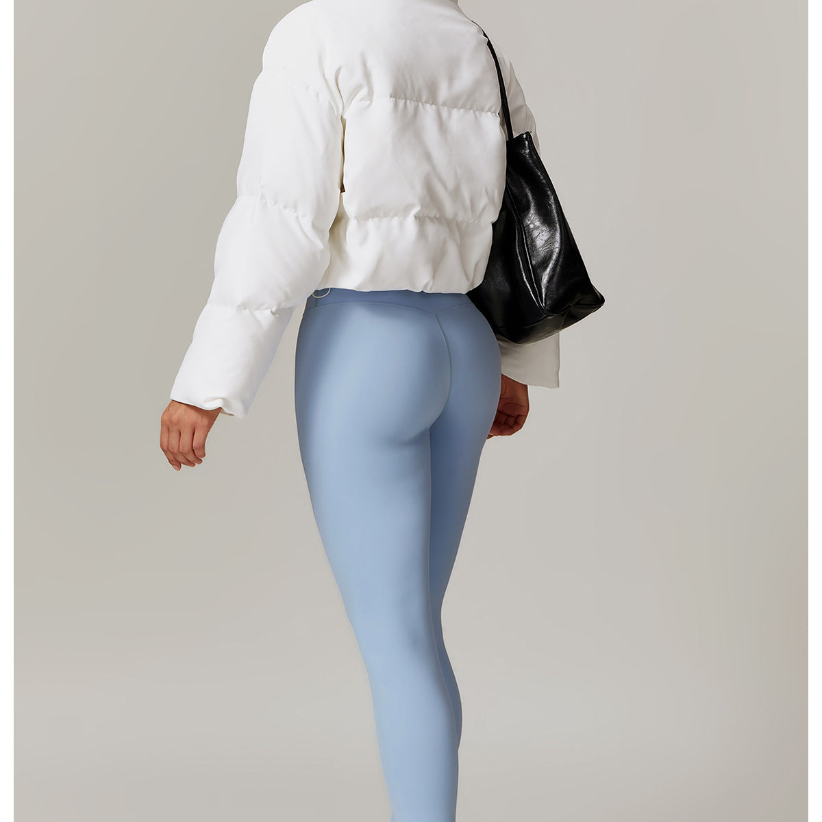 Woman in white puffer jacket and blue leggings, stylish ملابس fashion for cold weather