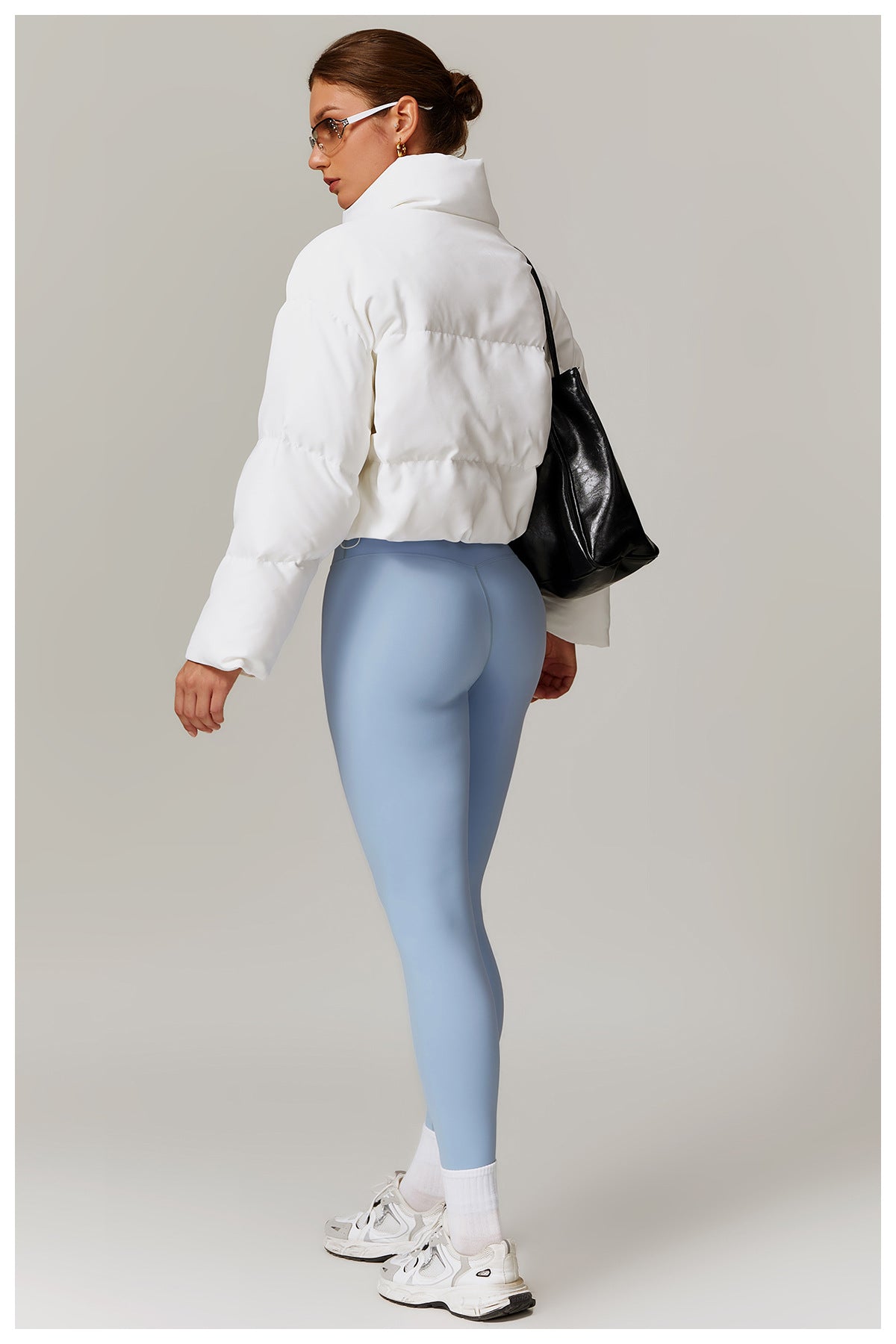 Woman in white puffer jacket and blue leggings, stylish ملابس fashion for cold weather