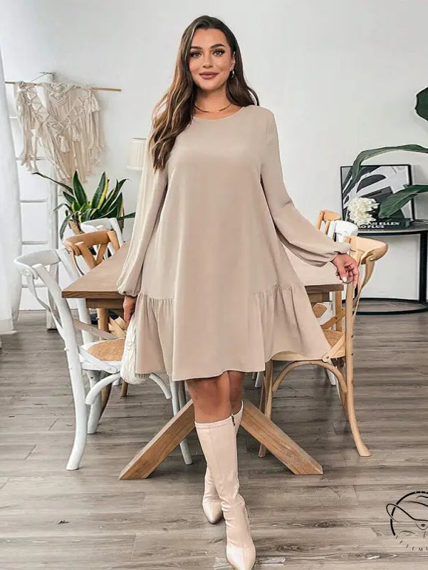 Woman in beige midi dress with ruffled hem and knee-high boots